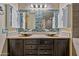 Bright bathroom featuring double sinks with vessel basins, wooden cabinets and accent backsplash and storage cabinets at 18495 W Rimrock St, Surprise, AZ 85388