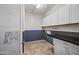Well-lit laundry room features modern cabinets, a dark countertop, and stylish tile flooring at 18495 W Rimrock St, Surprise, AZ 85388