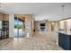 Open-concept living area with stone accent wall, electric fireplace, tile floors, and sliding door to the patio at 18495 W Rimrock St, Surprise, AZ 85388