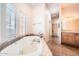 This bathroom features a soaking tub with large windows, tiled floors, and a separate sink and cabinet area at 19834 W Minnezona Ave, Litchfield Park, AZ 85340