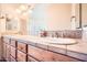 This bathroom features double sinks with stone countertops, light wood cabinets, and decorative light fixtures at 19834 W Minnezona Ave, Litchfield Park, AZ 85340