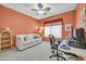 Bright bedroom with orange walls, a white sofa, desk with computer, and a ceiling fan at 20215 N Mariposa Way, Surprise, AZ 85374