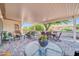 Inviting covered patio with brick pavers, outdoor seating, and lush landscaping at 20215 N Mariposa Way, Surprise, AZ 85374