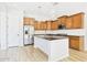 Modern kitchen with stainless steel appliances, wood cabinets, black countertops, and wood-style tile flooring at 20615 W Daniel Pl, Buckeye, AZ 85396