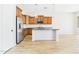 Modern kitchen with stainless steel appliances, wood cabinets, black countertops, and wood-style tile flooring at 20615 W Daniel Pl, Buckeye, AZ 85396