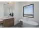 Modern bathroom featuring a freestanding soaking tub, sleek fixtures, and a bright window at 2087 N 77Th Pl, Mesa, AZ 85207