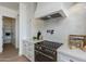 Close-up of a stylish kitchen with white cabinets, designer backsplash, and a modern stovetop with a sleek range hood at 2087 N 77Th Pl, Mesa, AZ 85207