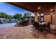 Relaxing covered patio with outdoor dining area, scenic pool views, and lush landscaping at 2107 E Park Ave, Gilbert, AZ 85234