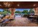 Charming covered patio with stone floors, outdoor lighting, and a serene view of the pool area at 2107 E Park Ave, Gilbert, AZ 85234