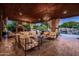 Relaxing covered patio with elegant chandelier, outdoor fireplace, and a view of the pool with a waterfall at 2107 E Park Ave, Gilbert, AZ 85234