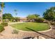 Large front yard with a garage, mature trees, a well-maintained lawn, and gravel landscaping at 2107 E Park Ave, Gilbert, AZ 85234