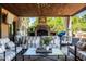 Inviting outdoor living space featuring a fireplace, comfortable seating, and a view of the trees at 2107 E Park Ave, Gilbert, AZ 85234