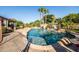 Stunning backyard pool area with a rock waterfall, jacuzzi, palm trees, and ample space for leisure at 2107 E Park Ave, Gilbert, AZ 85234