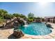 Inviting backyard pool featuring a rock waterfall, surrounding lush greenery, and a covered pergola at 2107 E Park Ave, Gilbert, AZ 85234