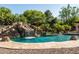 Swimming pool with rock waterfall feature, a slide, and lush landscaping offers a private backyard retreat at 2107 E Park Ave, Gilbert, AZ 85234