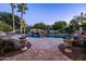 Beautiful swimming pool features a rock waterfall feature, mature palms, and ample patio space at 2107 E Park Ave, Gilbert, AZ 85234