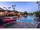 Backyard with pool, rock waterfall, red lounge chairs, and tall mature palm trees at 2107 E Park Ave, Gilbert, AZ 85234