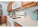 This kitchen has a white stove and microwave with brown cabinets and light countertops at 2327 E Meadow Creek Way, San Tan Valley, AZ 85140