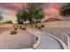 Walking path with a concrete retaining wall leading to neighborhood grounds with bushes, rock and sunset backdrop at 2343 E Morelos St, Chandler, AZ 85225
