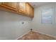 Bright laundry room features tile flooring, wood cabinets, and natural light from a window at 2421 W Indigo Dr, Chandler, AZ 85248