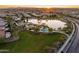 Aerial view showcases community with lake, playground, and lush green spaces at sunset at 3664 E Narrowleaf Dr, Gilbert, AZ 85298