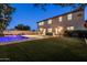 A beautiful backyard with a sparkling pool, lush green grass, and a modern home exterior at twilight at 3664 E Narrowleaf Dr, Gilbert, AZ 85298