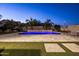 Expansive backyard featuring a pool with a stone accent wall, lush greenery, and travertine tile decking at 3664 E Narrowleaf Dr, Gilbert, AZ 85298
