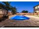 Inviting backyard featuring a pool with a stone waterfall, a basketball hoop, and elegant travertine tile at 3664 E Narrowleaf Dr, Gilbert, AZ 85298