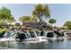 Beautiful community entrance with a rock waterfall feature and welcoming signage amidst lush landscaping at 3664 E Narrowleaf Dr, Gilbert, AZ 85298