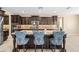 A kitchen island features dark wood cabinets, a granite countertop, seating, and a stylish faucet and sink at 3664 E Narrowleaf Dr, Gilbert, AZ 85298