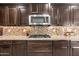 A close-up view of a kitchen features stainless steel appliances, wood cabinetry, and a decorative backsplash at 3664 E Narrowleaf Dr, Gilbert, AZ 85298