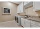 Modern laundry room with white cabinets, stainless steel appliances, and stylish tile backsplash at 5420 E Duane Ln, Cave Creek, AZ 85331