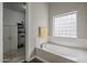 Bright bathroom featuring a soaking tub with tile surround and glass block window, plus built-in linen storage at 797 E Cedar Dr, Chandler, AZ 85249