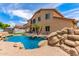 Expansive backyard with a sparkling pool, rock features, tropical palms, and a covered patio area at 84 E Joseph Way, Gilbert, AZ 85295