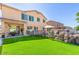 Lush backyard with artificial turf, mature trees, a fenced pool, and a covered patio, perfect for relaxing outdoors at 84 E Joseph Way, Gilbert, AZ 85295