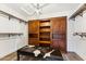 Spacious walk-in closet boasts custom wooden storage and shelving and an ottoman seating area at 9801 W Rockwood Dr, Peoria, AZ 85382
