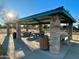 Shady park pavilion with stone pillars, picnic tables, and trash receptacle at 11048 E Quintana Ave, Mesa, AZ 85212