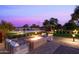 Outdoor fire pit with comfortable seating, set against a backdrop of a beautifully landscaped backyard and twilight sky at 11601 N 64Th Pl, Scottsdale, AZ 85254