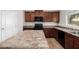 Kitchen featuring an island with stone countertops, dark wood cabinets, and black appliances at 14129 W St Moritz Ln, Surprise, AZ 85379