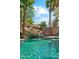 Backyard pool features a rock waterfall with palm trees and blue skies above at 14364 W Cameron Dr, Surprise, AZ 85379