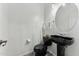 Sleek powder room featuring modern fixtures and a round mirror above a dark pedestal sink at 14364 W Cameron Dr, Surprise, AZ 85379