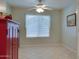 A bright bedroom features tile flooring, a ceiling fan, and a window with lace curtains at 17765 W Ventura St, Surprise, AZ 85388