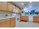 Kitchen with ample wood cabinets, white appliances, and a breakfast bar overlooking another room at 17765 W Ventura St, Surprise, AZ 85388