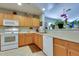 Well-maintained kitchen with wood cabinets, white appliances, and a breakfast bar to the living space at 17765 W Ventura St, Surprise, AZ 85388