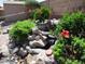 Backyard featuring flower and plant beds, green shrubs, rock features and a small waterfall feature at 1819 E Sheena Dr, Phoenix, AZ 85022