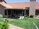 Backyard with flowers, green lawn and a covered seating area with outdoor furniture and sun shades at 1819 E Sheena Dr, Phoenix, AZ 85022