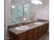 Bathroom featuring double sinks with granite countertop and wood cabinets, with tiled shower at 1819 E Sheena Dr, Phoenix, AZ 85022