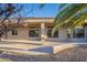 The covered back patio has tan flooring, a rock garden, and views of mature foliage at 19608 N Regents Park Dr, Surprise, AZ 85387