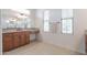 Bright bathroom featuring double windows, neutral tile flooring, granite vanity, and expansive mirror at 27380 N 128Th Ln, Peoria, AZ 85383