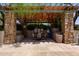 A covered outdoor seating area features stone pillars, shade, and a table with chairs at 27380 N 128Th Ln, Peoria, AZ 85383